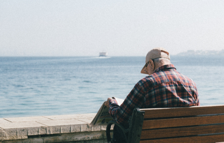 Retiree reading newspaper by the ocean