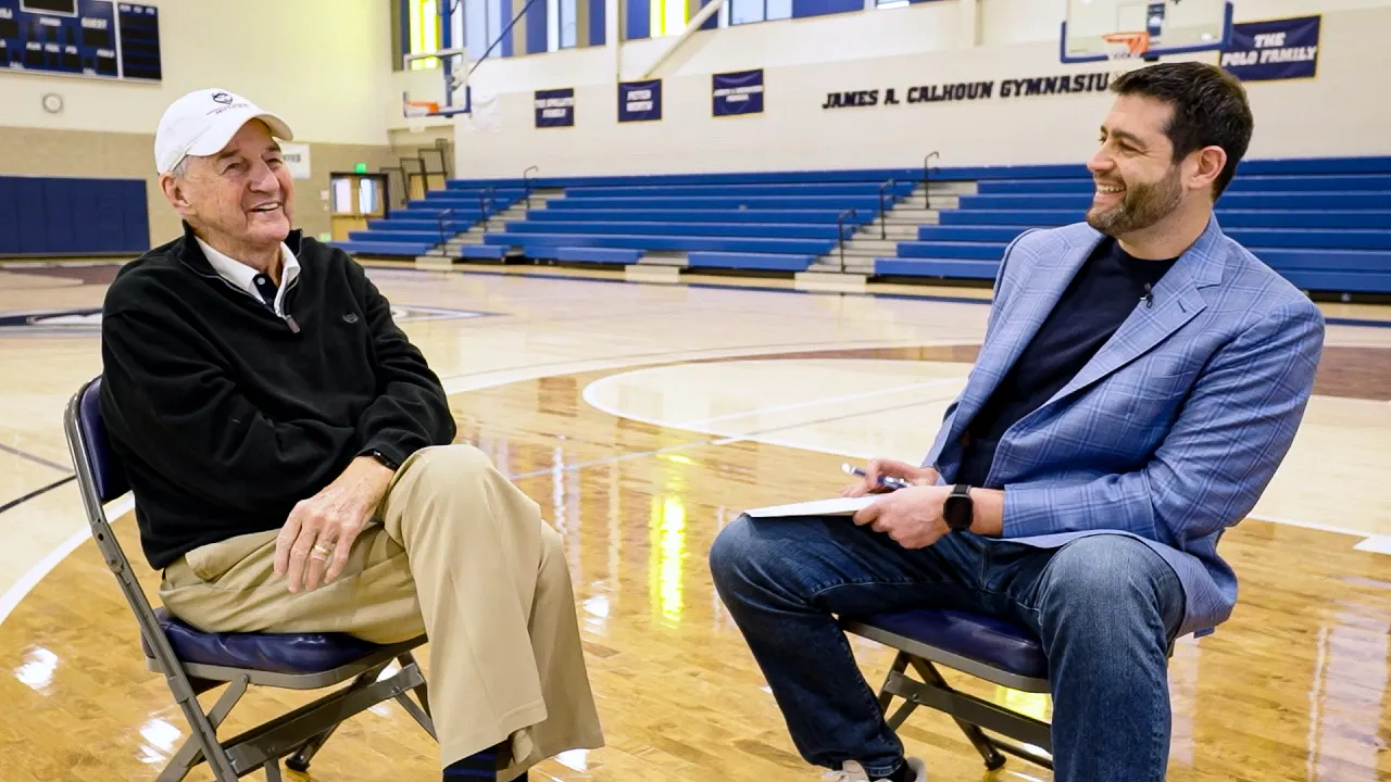 Ben Fuchs and Jim Calhoun sitting at a basketball.